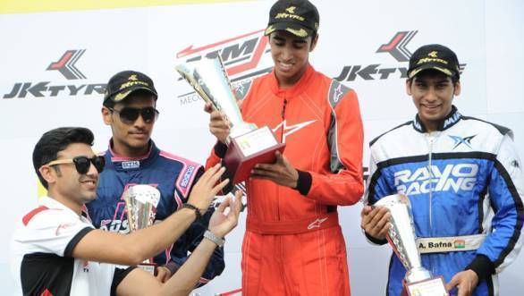 Ricky Donison accepts the trophy for first place in the Senior Max class, as Ameya Bafna and Nayan Chatterjee who finished second and third look on