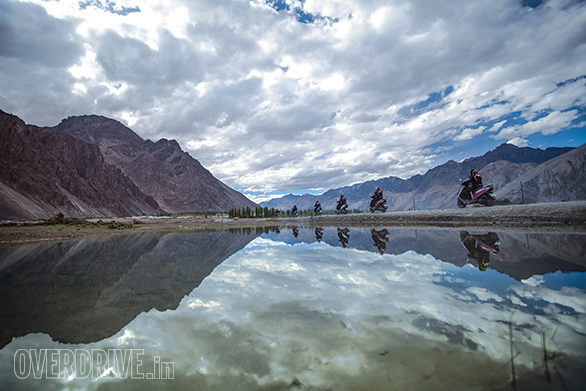 The rare appearance of lush green and flowing water marks the lush Nubra Valley plain through which the Shyok River flows with great urgency. Here the girls of the TVS Himalayan Highs Season 2 ride back to the main road after meeting the Bactrian camels of Hunder